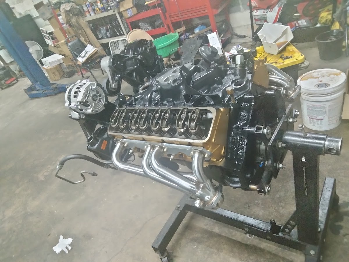 A rebuilt V8 engine on a stand with new headers at Motor Man's shop